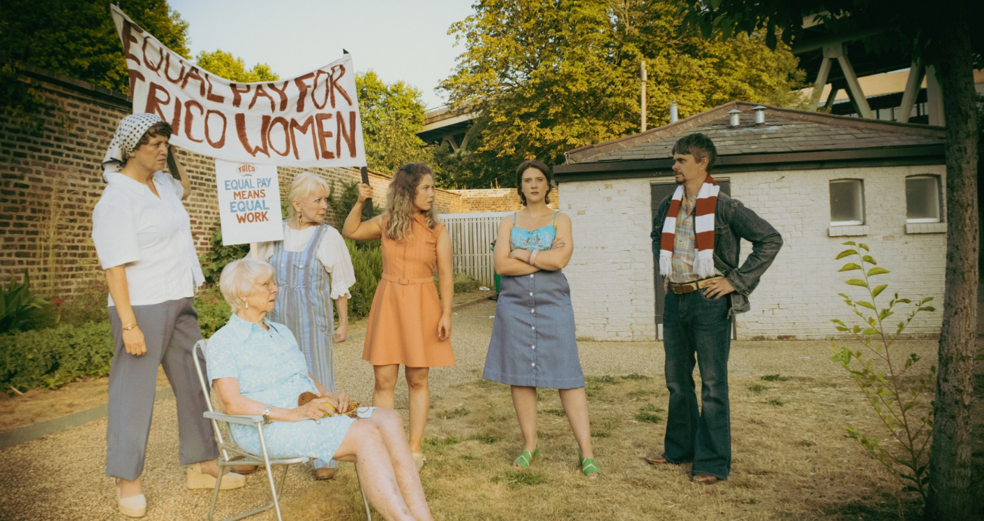 A group of female protesters on the left hold up a sign that reads 